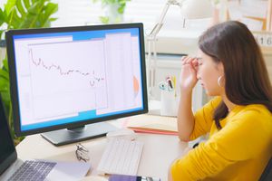 Woman looking at a chart showing a downtrend, displayed on her computer.