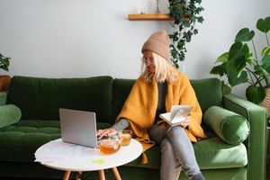 Woman sitting on a green couch, looking at her computer.