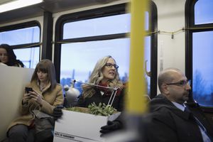 Laid-off businesswoman commuter riding bus with box of belongings