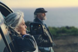 Older couple starting out the car window at a sunset.