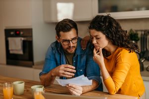 A couple sitting at a kitchen table reviewing documents together