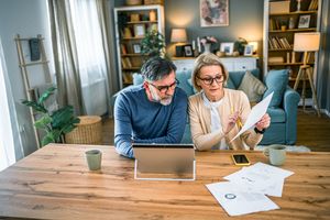 Older couple sitting at a table reviewing documents with a tablet