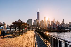 A waterfront promenade leading to a view of a city skyline at sunrise
