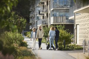 An older couple walks past a younger couple pushing a baby stroller in a residential outdoor area