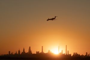 Airplane flying over city skyline at sunset