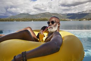Person relaxing on a pool float with a water and mountain landscape in the background