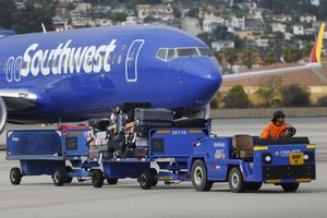 Southwest Airlines plane at an airport with a baggage vehicle towing luggage carts