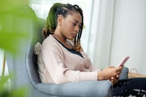 A seated individual looking at a phone in a living room setting
