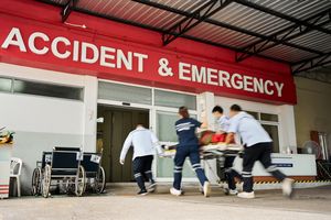 Medical personnel rushing a patient on a stretcher into the Accident and Emergency entrance of a hospital