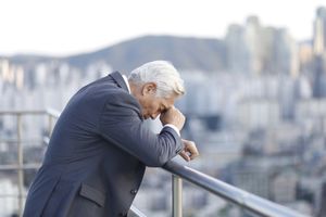 Thoughtful senior businessman leaning on balcony railing