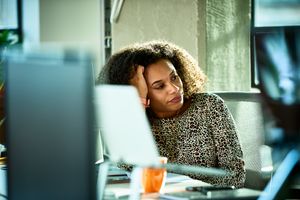 Person sitting at a desk appearing thoughtful in an office setting