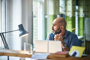 A man sitting at a desk pauses in thought.