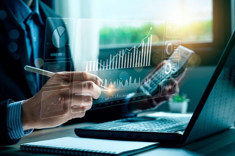 A person has a pen touching a virtual screen with a laptop behind it.