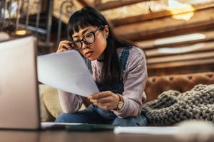 A woman looking at papers in front of a computer
