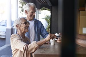 Two elderly individuals one receiving a cup at a service counter