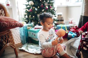 A little girl looks at a doll on Christmas morning