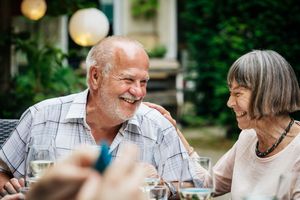 Older couple smiling and enjoying a social gathering.