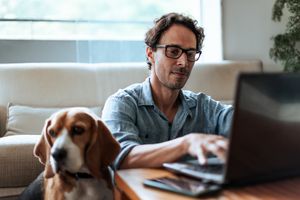 A man with a dog at a computer