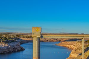 A concrete bridge support over a large body of water in a rocky landscape