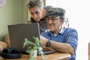 Two individuals interacting with a laptop at a table