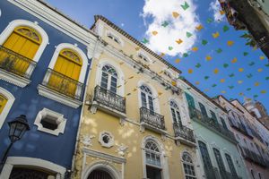 Colorful colonialstyle buildings with arched windows and balcony railings festive triangular flags strung across the scene