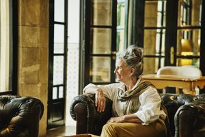 A person sitting on a chair in a room with large glass doors looking to the side