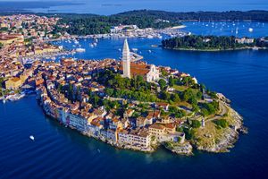 View of a coastal town built on a peninsula with a prominent church steeple surrounded by water and a marina nearby