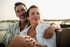 A couple sitting together and smiling on a boat with a marina in the background
