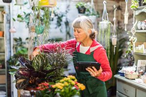 A woman arranging plants in a shop holding a tablet