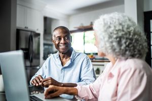 Two people having a conversation at a table in a kitchen with a laptop