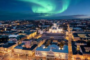 Aurora borealis above a city skyline featuring a central illuminated cathedral at night a cityscape with lights and streets