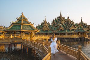 A woman crosses a bridge at a temple in Thailand. 