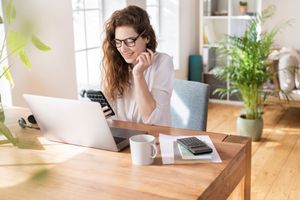 A woman with a calculator sits at a desk.