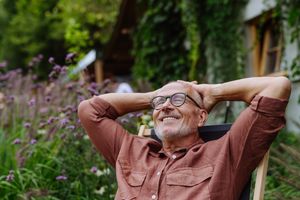 Man relaxing outdoors in a garden setting leaning back on a chair